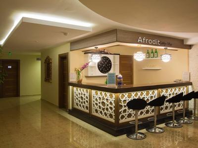 Moderne Hotelbar mit schwarzer Theke, Barhockern und dekorativem Beleuchtungselement an der Decke.