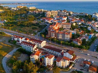 Luchtfoto van een kustplaats met woongebouwen, wegen en zee op de achtergrond.