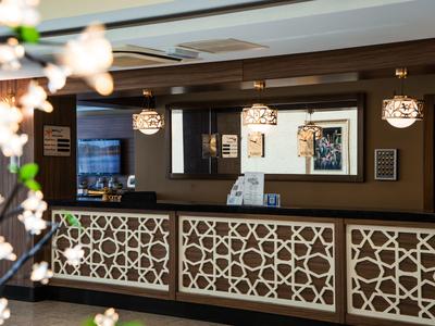 Hotelreceptiebalie met decoratief patroon en drie hanglampen.