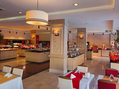 Modern hotelrestaurant met gedekte tafels en buffetgedeelte onder warm licht.