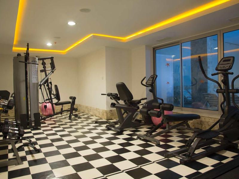 Siłownia z różnymi urządzeniami do ćwiczeń i podłogą w kratę w nowoczesnym stylu.