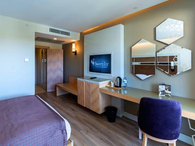 Modern ingerichte hotelkamer met bureau, tv en decoratieve wandspiegels.