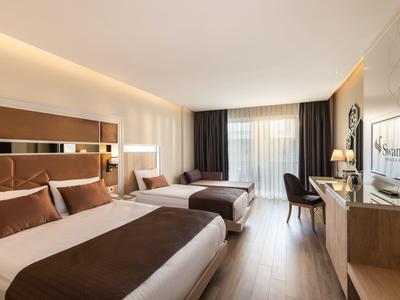 Lichte tweepersoonskamer met twee bedden, bureau, stoel en tv in een modern hotel.