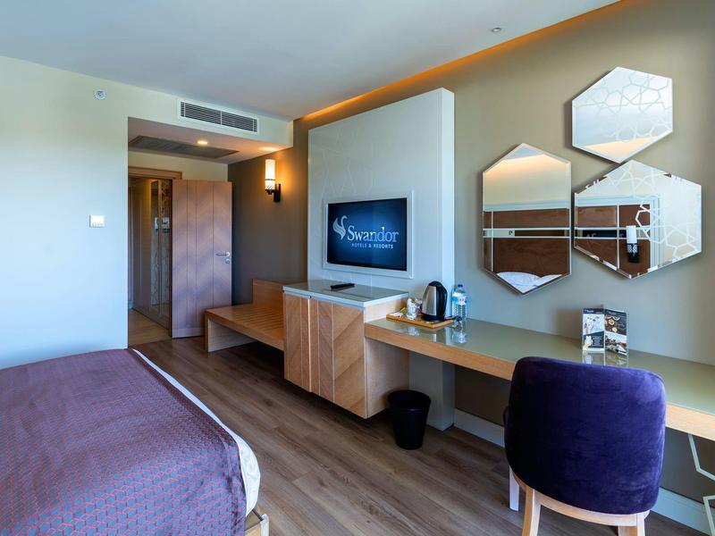 Modern ingerichte hotelkamer met bureau, tv en decoratieve wandspiegels.