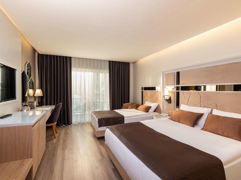 Moderne hotelkamer met twee bedden, bureau en balkon met gordijnen.