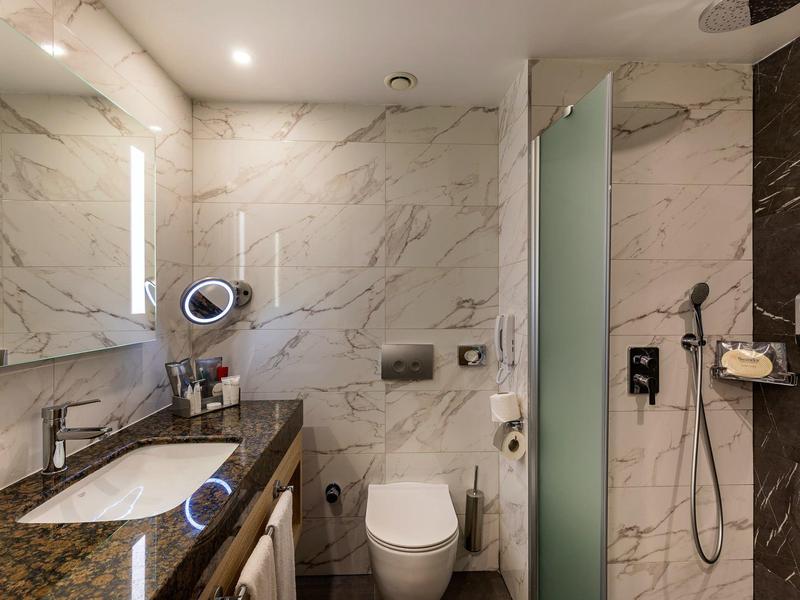 Elegant badkamer met marmeren muren, wastafel, toilet en inloopdouche in een hotel.
