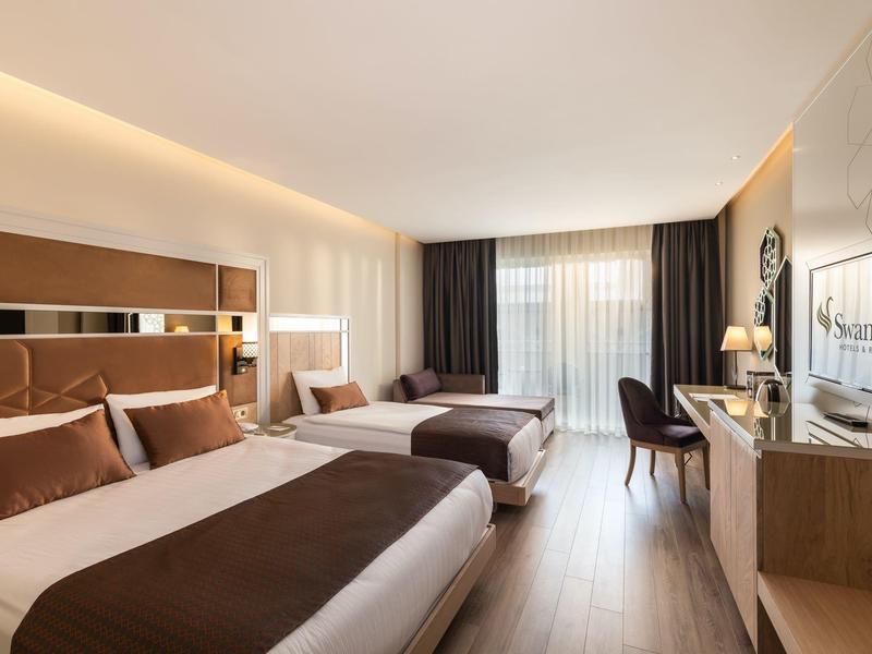 Lichte tweepersoonskamer met twee bedden, bureau, stoel en tv in een modern hotel.