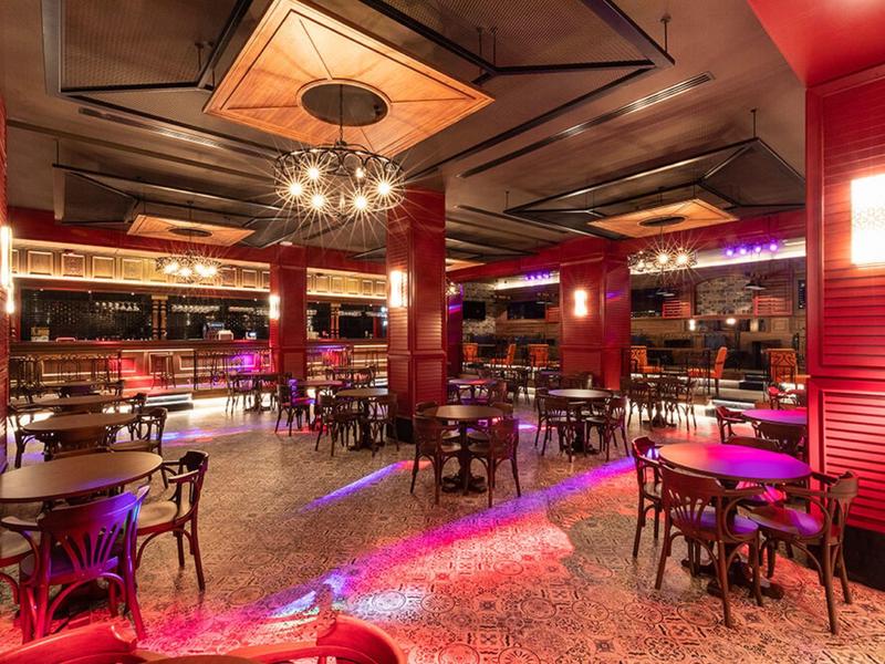 Moderne hotelbar met rood verlichte inrichting en donker houten meubels.