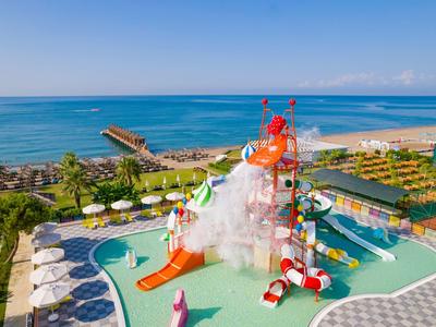 Wasserpark mit farbenfrohen Wasserrutschen und Planschbecken am Strand mit Blick auf das Meer.