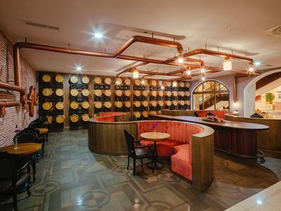 Gemütliche Bar mit runden Sitznischen, Stühlen und dekorativen Holz- und Kupferdetails.