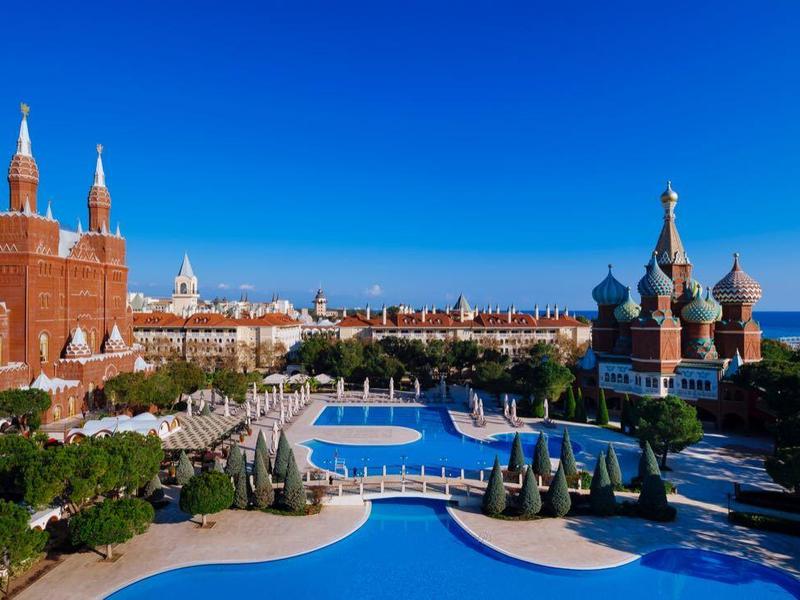 Luxuriöses Hotel mit mehreren Pools und malerischer Aussicht auf das Meer und historische Gebäude.
