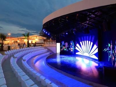 Palco all'aperto illuminato con file di sedili in un resort alberghiero al crepuscolo.