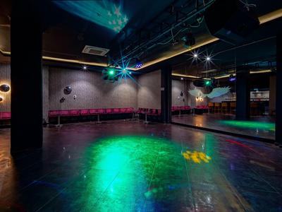 Sala da ballo moderna con illuminazione, parete a specchio e area salotto.