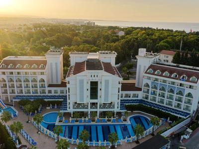 Veduta aerea di un grande hotel con piscine e giardini al tramonto.