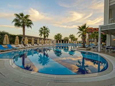 Piscina rotonda con palme e lettini in un hotel al tramonto.