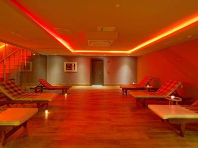 Salle de détente avec chaises longues et lumière orange chaude dans un hôtel moderne.