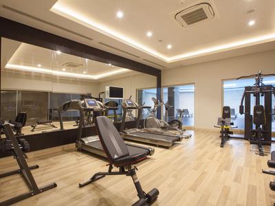 Palestra moderna con varie attrezzature e grandi specchi alle pareti.