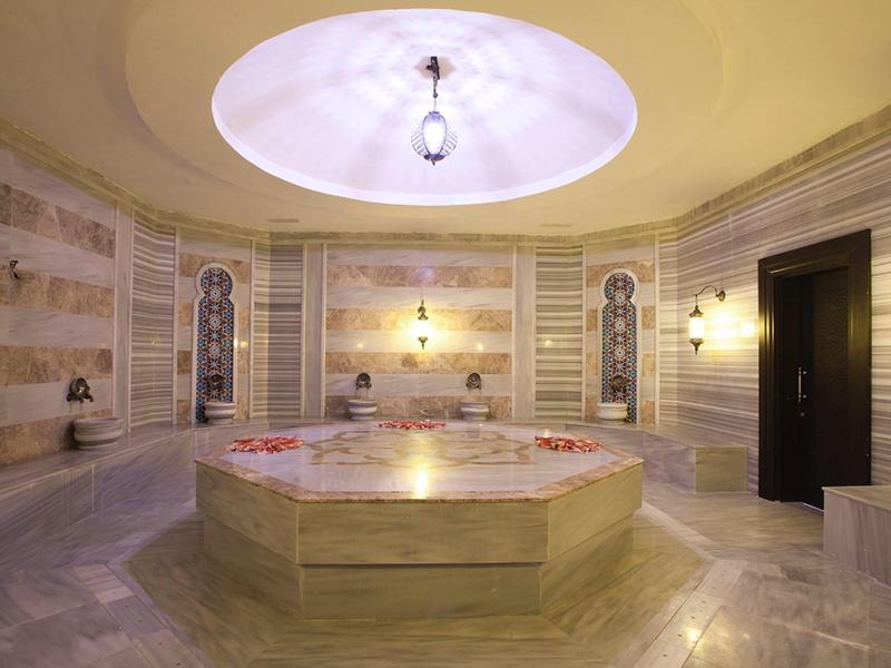 Intérieur d'un hammam turc avec un bassin central en marbre et un éclairage doux.