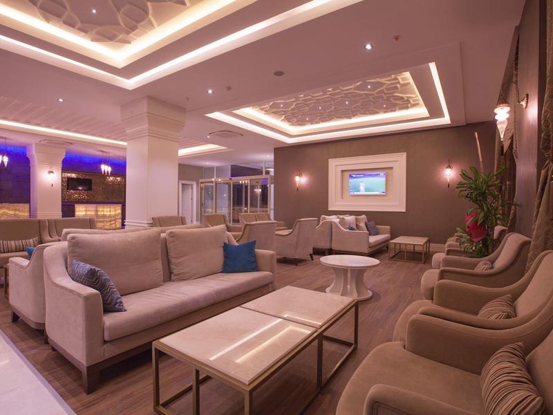 Salon d'hôtel élégant avec canapés confortables, fauteuils et éclairage moderne.