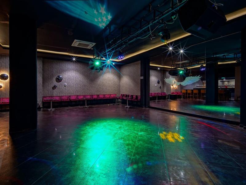 Salle de club sombre et vide avec lumières disco et mur miroir.