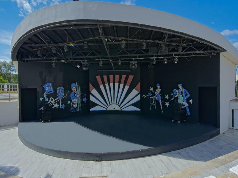 Scène en plein air avec toit en demi-cercle couvert et décor de fond avec motif de rayons de soleil