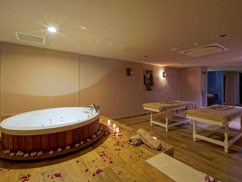 Une salle de spa sereine avec un jacuzzi, des tables de massage et un éclairage doux.