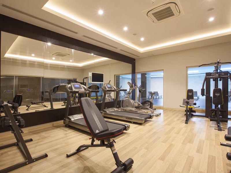 Salle de sport moderne avec différents équipements d'entraînement et sol en bois.