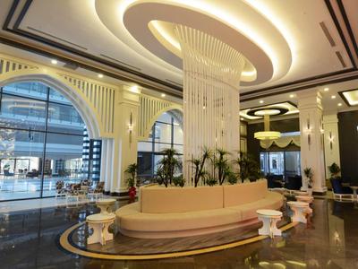 Luxe hotelhal met moderne kroonluchter, gebogen zitplaatsen en grote ronde ramen.