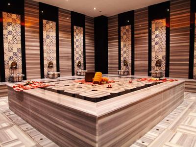 Luxe spa-ruimte met centrale marmeren massagetafel versierd met handdoeken en decoratie.