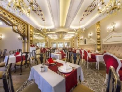 Elegante hotel-eetzaal met sierlijke kroonluchters en rood gestoffeerde stoelen.