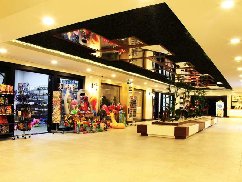 Ruimtelijk winkelgebied in een hotel met winkels, zitplaatsen en heldere verlichting.