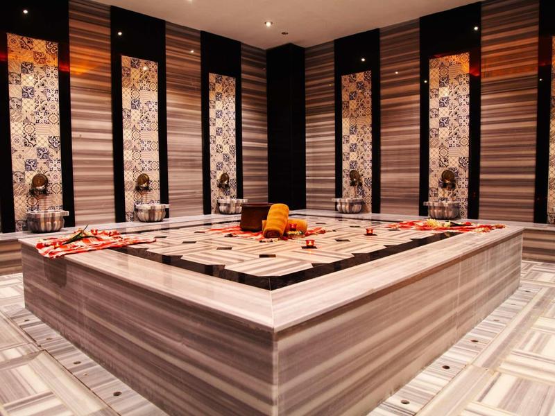 Luxe spa-ruimte met centrale marmeren massagetafel versierd met handdoeken en decoratie.