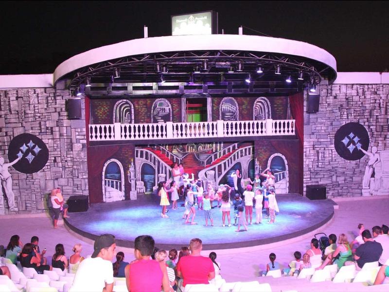 Podiumoptreden met dansers voor zittend publiek in een ronde, steenachtig theater.
