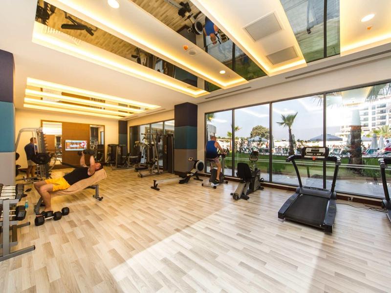 Ruime sportschool met moderne apparatuur en grote ramen met uitzicht op buitenterrein.