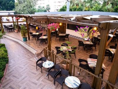 Zewnętrzny taras z drewnianymi meblami i stołami udekorowanymi kwiatami w ogrodzie hotelu.