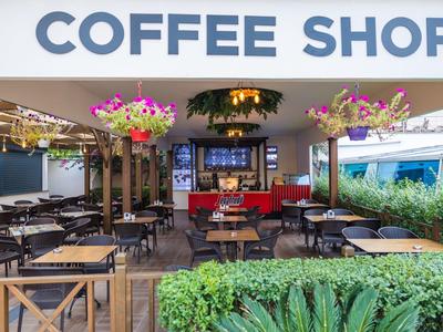 Przytulna kawiarnia z miejscami na zewnątrz i wiszącymi kwiatami.