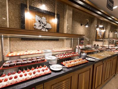 Bufet z różnymi deserami w hotelowym otoczeniu z ciepłym oświetleniem.