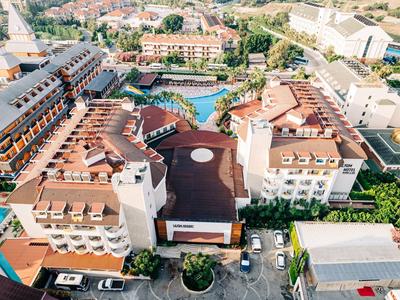 Widok z lotu ptaka na duży hotel z basenem i wieloma miejscami parkingowymi w mieście.