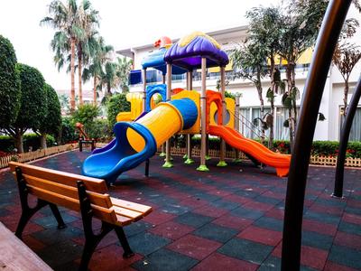 Kolorowy plac zabaw dla dzieci ze zjeżdżalniami i ławkami w hotelowym ogrodzie.