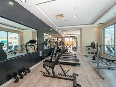 Gimnasio moderno con equipo de ejercicio y grandes ventanas con vista a la ciudad.