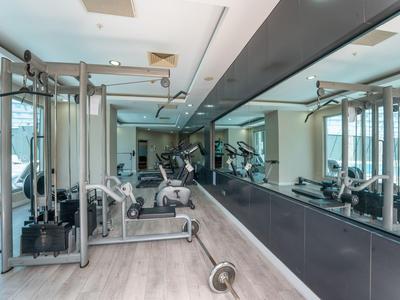Gimnasio moderno con varios equipos de ejercicio y paredes con espejos en un hotel.