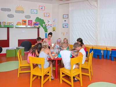 Niños sentados en mesas coloridas en una sala luminosa y apta para niños en el hotel.