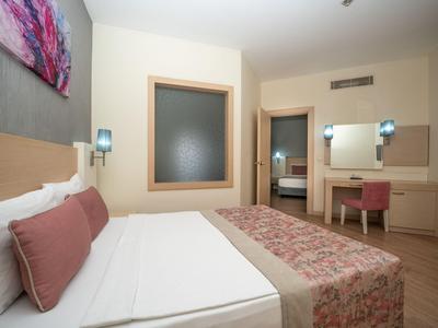 Habitación de hotel moderna con cama doble, colores neutros y suelo de madera.