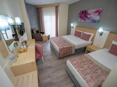 Habitación de hotel luminosa con dos camas, área de estar y escritorio.