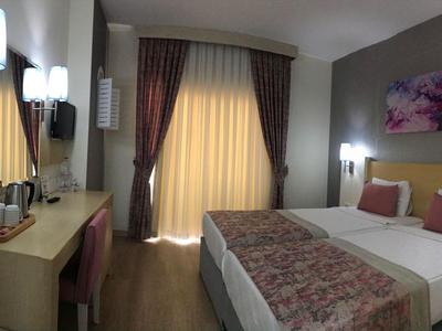 Modern hotelkamer met tweepersoonsbed, bureau en gordijnen voor balkonramen.