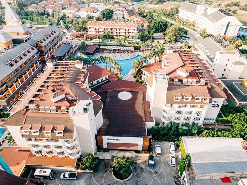 Widok z lotu ptaka na duży hotel z basenem i wieloma miejscami parkingowymi w mieście.