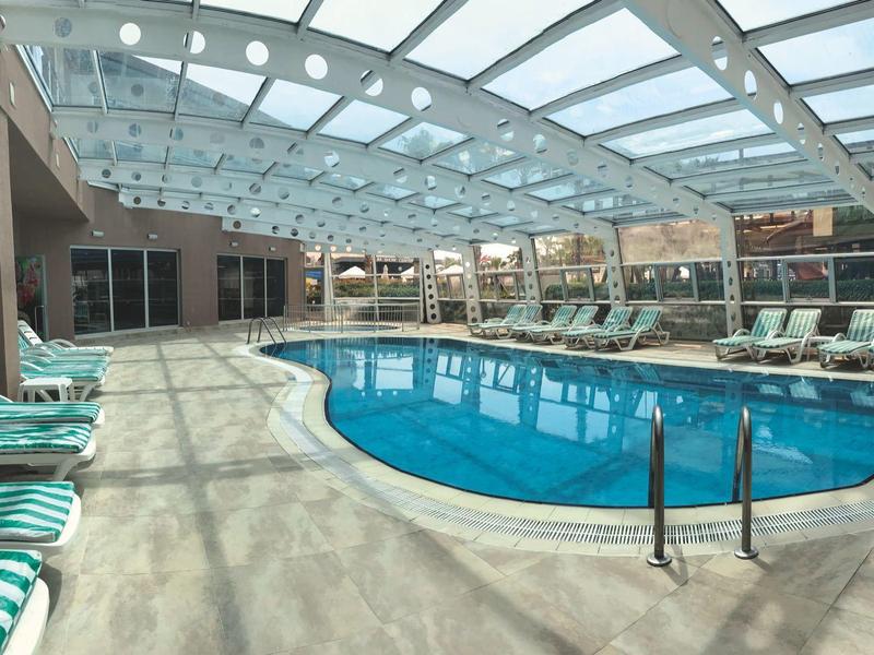 Jasny basen kryty ze szklanym dachem i leżakami