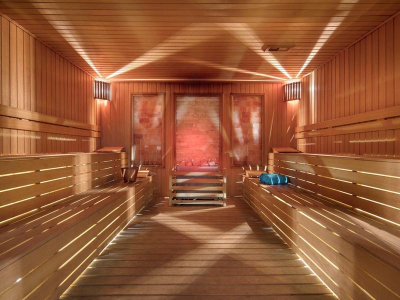Przytulne wnętrze sauny z drewnianymi ławkami i miękkim oświetleniem.