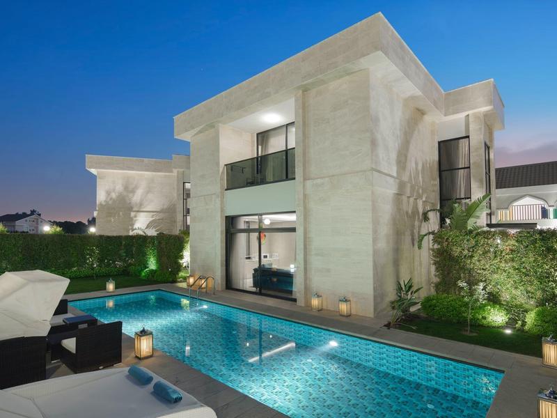 Nowoczesna willa z oświetlonym basenem i wygodnymi meblami na zewnątrz.
