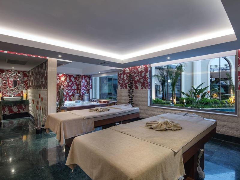 Elegancki pokój do masażu z dwoma stołami, roślinami i naturalnym światłem.